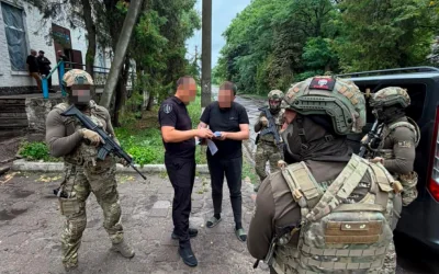 Військові в камуфляжі з автоматами біля двох чоловіків у чорному та автомобіля