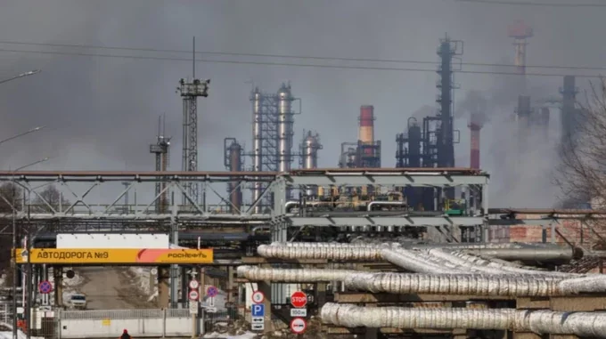 Нефтеперерабатывающий завод Роснефть с дымящимися трубами, трубопроводами и дорожными знаками